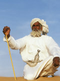 Bedouin Man Kneels on Top of a Sand Dune in the Desert Photographic Print by John Warburton-lee