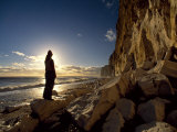 Silhouetted Figure Admires the Dramatic Coastal Landscape at Newhaven Photographie par Fergus Kennedy