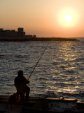 Fisherman Watches as the Sun Goes Down on the Waterfront of Alexandria, Egypt Photographic Print by Julian Love