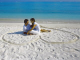 Young Couple on Beach Sitting in a Heart Shaped Imprint on the Sand, Maldives, Indian Ocean, Asia Photographic Print by Sakis Papadopoulos