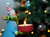 Close-Up of a Snow Man Candle in Front of a Tree with Christmas Lights Photographie par Images Monsoon