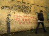Pedestrian Walks Past Humorous Anti Graffiti on a Street in Dunedin Photographie par Bill Hatcher