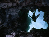Looking Through a Hole in Volcanic Rock at Blue Water Above Photographic Print by Mattias Klum