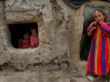 Displaced Girls Smile as They Look Out from a Shanty, in a Refugee Camp in Kabul, Afghanistan Photographie