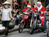 Vietnamese Men Dressed as Santa Claus Wait on their Motorbikes on a Street in Hanoi, Vietnam Lámina fotográfica Vietnamese Men Dressed as Santa Claus Wait on their Motorbikes on a Street in Hanoi, Vietnam Lámina fotográfica