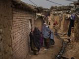 Three Afghan Refugee Women and their Children Walk in an Alley of a Poor Neighborhood in Pakistan Photographie