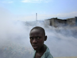 Youth Walks by Burning Garbage in Cite Soleil, Port-Au-Prince Photographic Print