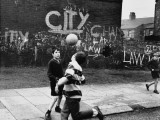 Boys Play Football in the Street - Moss Side, Manchester Fotografisk trykk av Shirley Baker