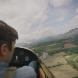 Man in Airplane Cockpit Looking Out at Fields Below Photographic Print by Dennis Hallinan
