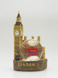 Close-Up of a Toy Bus in a Snow Globe in Front of a Figurine of a Clock Tower Photographic Print