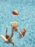 Family Tossing Beach Ball While Floating on Pool Rafts Photographic Print by Dennis Hallinan