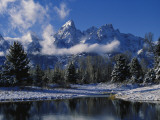 Winter Scene of Clouds Drifting across Snowy Mountain Peaks Above Pine Trees Is Reflected in Water Fotografisk trykk av Jeff Foott Winter Scene of Clouds Drifting across Snowy Mountain Peaks Above Pine Trees Is Reflected in Water Fotografisk trykk av Jeff Foott