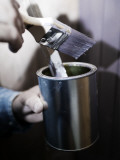Close-Up of a Person's Hand Holding a Paintbrush and a Paint Can Photographic Print