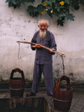 China, Anhui Province, Old Man Fetching Water with Buckets by the Well Photographic Print by Keren Su