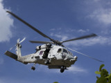 A Crew Chief Looks Out the Side Door of a Helicopter in Flight Lámina fotográfica