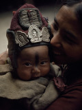 A Baby Wears a Protective Woolen Cap Adorned with Amulets and Needles Photographie par Lynn Abercrombie