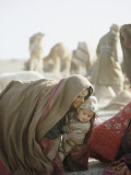 Wrapped Against Wind and Sand, a Kuchi Woman Lifts a Young Child Photographic Print by Thomas J. Abercrombie
