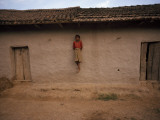 A Tharu Girl Perches on a Support Post of a Traditional Longhouse Photographic Print by Maggie Steber