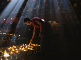 A Buddhist Monk Lights Devotional Lamps Inside Jokhang Temple Photographie par Maria Stenzel