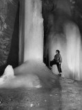 A Woman Standing Next to an Ice Pillar in a Cave Photographic Print by Norbert Casteret