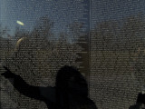 Shadow of a Woman Pointing to a Name on the The Vietnam Memorial Photographic Print by Todd Gipstein