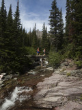 Two Hikers Cross a Small Stream in the Montana Backcountry Photographic Print by Michael Hanson