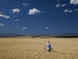 A Girl Wearing a Cowboy Hat Stands in a Wheat Field on a Sunny Day Photographic Print by Michael Hanson