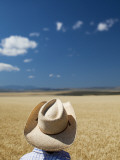 A Girl Wearing a Cowboy Hat Stands in a Wheat Field on a Sunny Day Photographic Print by Michael Hanson