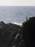 A Man's Fishing Line Shines in the Sunlight as He Fishes from a Rock Photographic Print by Michael Hanson