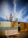 Pink Seat with Corrugated-Iron Fence Behind Photographic Print by John Sones