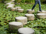 Man Crossing Stepping Stones across Soryu-Ike Pond in Naka Shin'En Garden Fotografie-Druck von Rachel Lewis