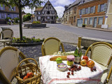 Cheese, Cherries, Apples and Champagne on Cafe Table with Half-Timbered House in Background Photographie par Barbara Van Zanten