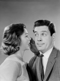 Woman Whispering Into Man's Ear, Man Pulling Funny Face Photographie par H. Armstrong Roberts