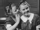 Girl Indoors Whispering Into Ear of Twin Sister Photographie par George Marks