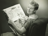 Woman Sitting in Armchair, Reading Newspaper, Smiling Photographic Print by George Marks