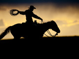 A Silhouetted Cowboy Riding Alone a Ridge at Sunset in Shell, Wyoming, USA Photographic Print by Joe Restuccia III