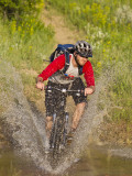 Mountain Biker Splashes Through Andrews Creek, Maah Daah Hey Trail in Medora, North Dakota, USA Photographie par Chuck Haney