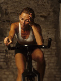 Young Woman Exercising on a Stationary Bike Photographic Print