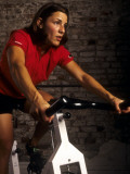 Young Woman Exercising on a Stationary Bike Photographic Print