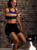 Young Woman Exercising on a Stationary Bike Checking her Heart Rate Photographic Print
