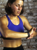 Young Woman Exercising on a Stationary Bike Checking her Heart Rate Photographie