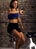 Young Woman Exercising on a Stationary Bike Checking her Heart Rate Photographie