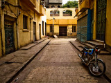 Back Street of Luxor Town, Egypt with Motorbike Photographie par Clive Nolan