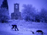 A Man Rolls a Ball of Snow Near the Church in Porqueres Photographie par Tino Soriano