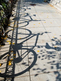 Shadows of Bicycles Cast on a Side Walk Photographic Print by Brian Gordon Green