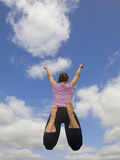 Young Woman Jumping, with a Cloud-Filled Sky in Front of Her Photographic Print by Joe Petersburger