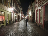 A Man Walks Down a Cobbled Street at Night Photographic Print by Greg Dale
