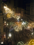 Festive Lights Span across Buildings over Pedestrians on the Street Impressão fotográfica por Luis Marden