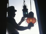 A Man Handles Red and Green Lanterns Hanging Near a Doorway Impressão fotográfica por Luis Marden