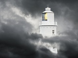 Lighthouse Emerging From Dark Clouds Photographic Print by Paul Hardy